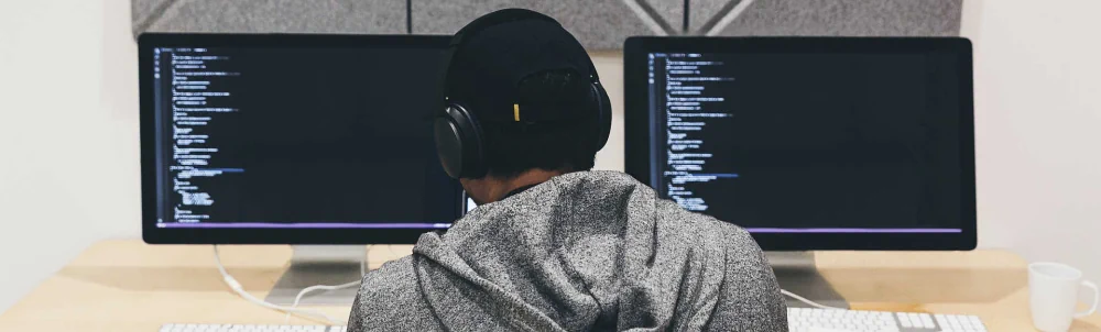 Focused Individual Reviewing Code on a Computer Screen at a Desk with code flowing all over the place.